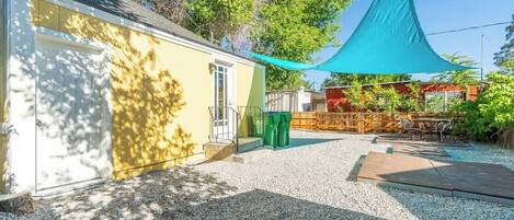 A house with a garage, a patio with outdoor furniture, and a green canopy.