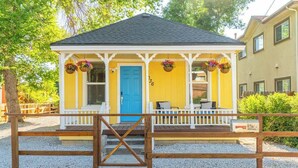 A small yellow building with a blue door, white porch, and a wooden gate. - Charming Family 2BR Midtown Reno - Pets Welcome (Reno)
