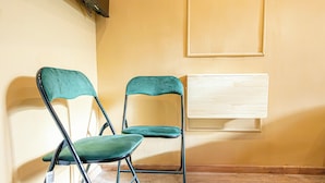 Dos sillas plegables color turquesa con estructura metálica, colocadas frente a una pared amarilla sobre suelo de madera.