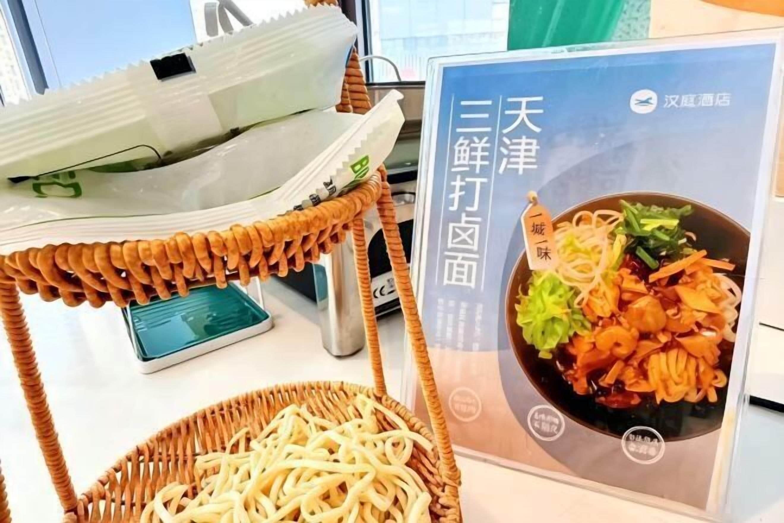 A dining area with a wicker chair, a smartphone on a table, and a poster of a dish.