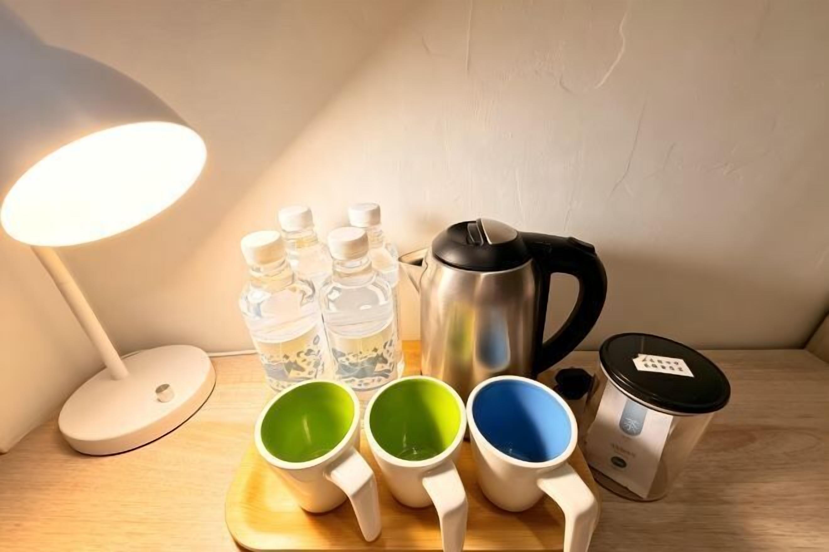 Une table avec une bouilloire, des bouteilles d’eau et des tasses à mesurer.