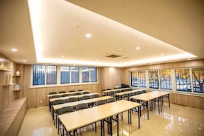 Une salle de conférence dotée de plusieurs tables et chaises, de grandes fenêtres offrant une vue dégagée et d’un décor intérieur en bois.