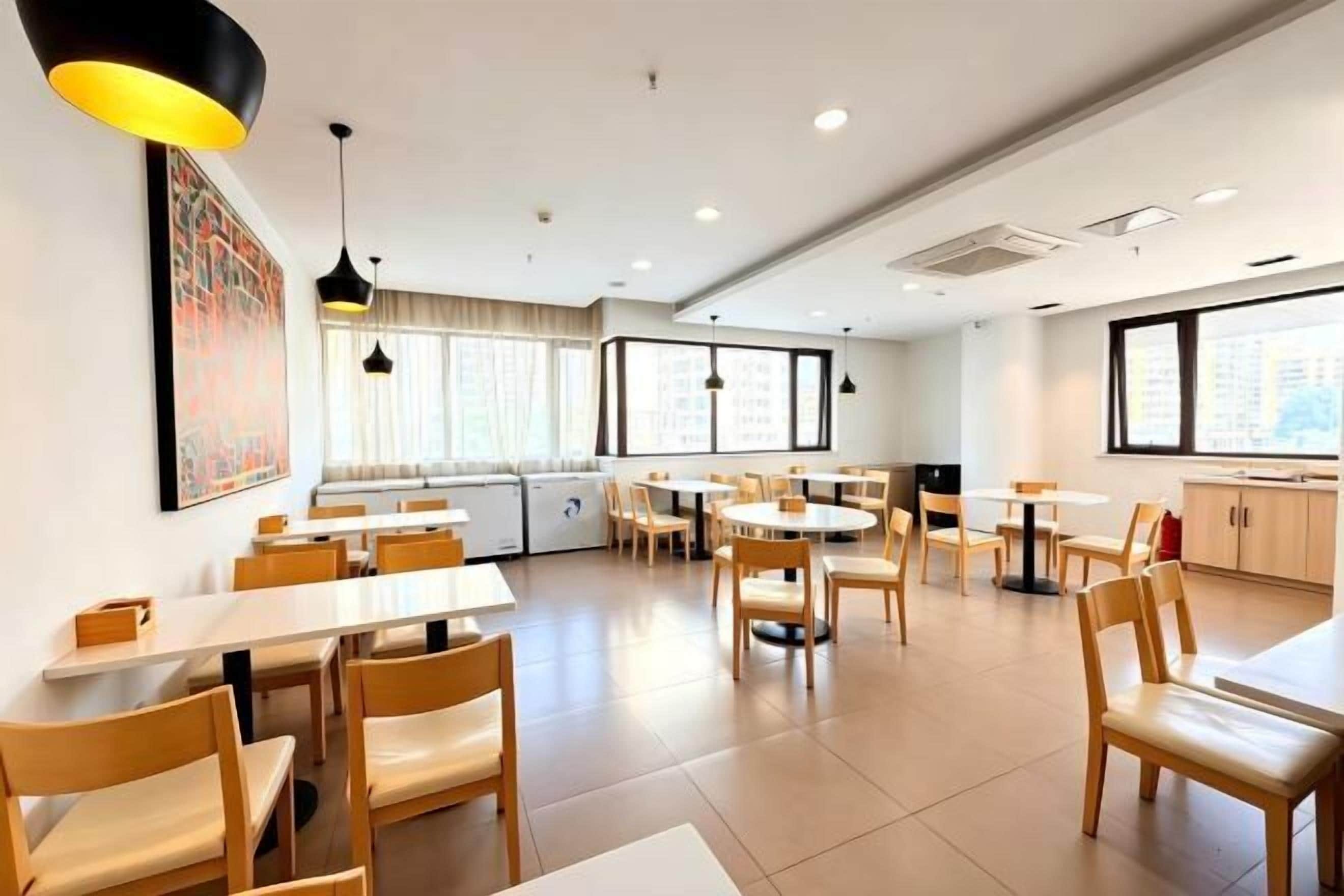 A modern dining area with tables and chairs, large windows, and pendant lighting.