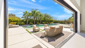 A modern outdoor living area with a pool, outdoor furniture, and a view of the surrounding landscape. - Model Perfect!  Rancho Mirage, Luxe Design, 3900sf!  Pool/Spa/Huge Yard (Rancho Mirage)