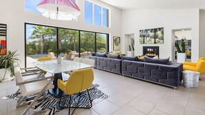 A spacious living area with a large glass wall, a modern sofa set, a dining table, and a zebra-patterned rug. - Model Perfect!  Rancho Mirage, Luxe Design, 3900sf!  Pool/Spa/Huge Yard (Rancho Mirage)