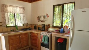 A kitchen with wooden cabinets, a stove, a sink, and a refrigerator.