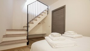Ein Schlafzimmer mit einem Bett, einer Treppe und einer Tür.