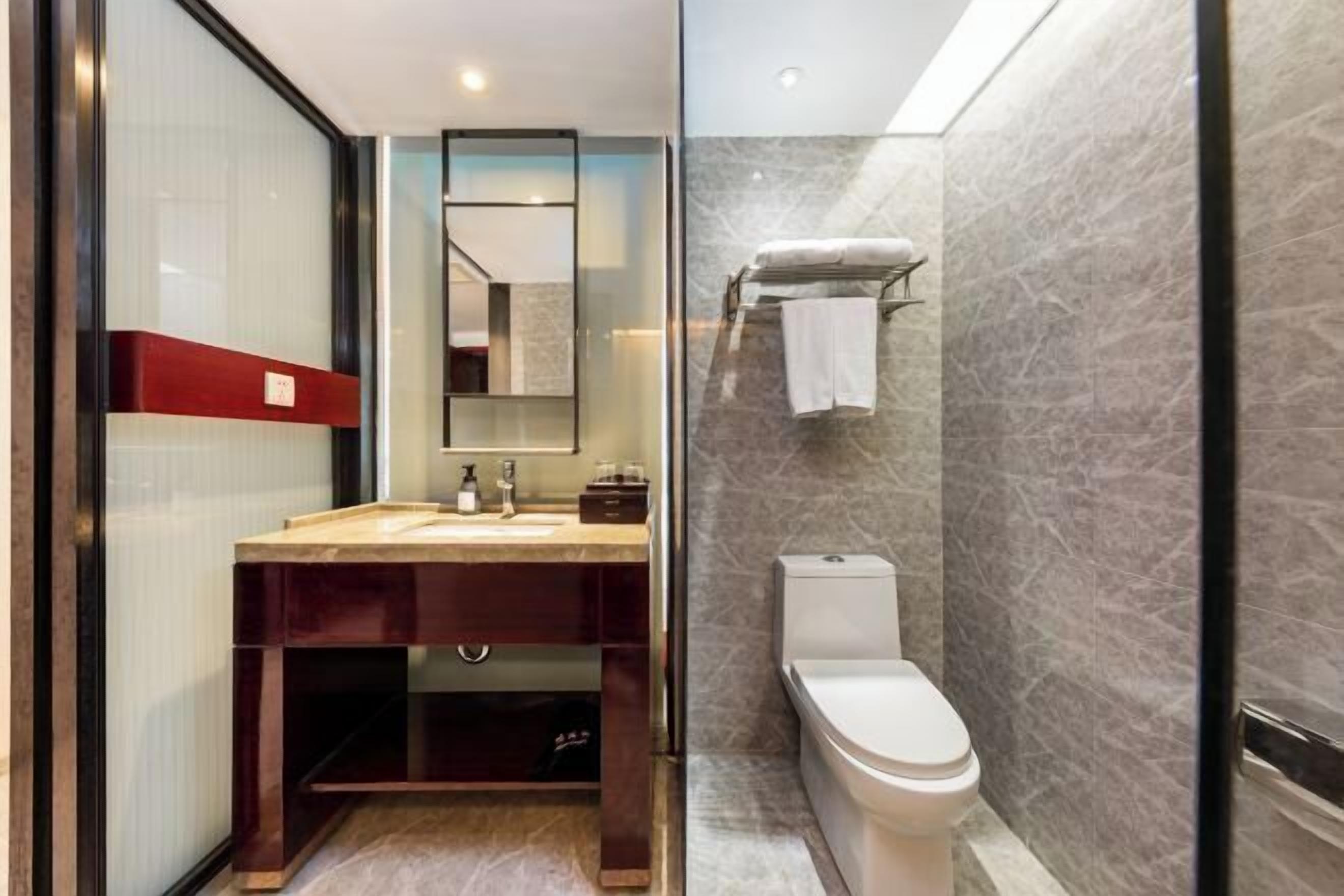 A modern bathroom with a glass shower enclosure, a wooden vanity, and a white toilet.