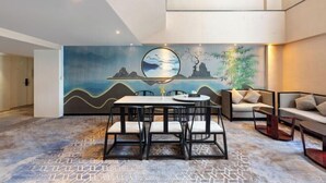 A modern hotel room with a dining area, a sofa set, and a decorative wall with a circular artwork. - Quanzhou City Holiday Hotel (Gucheng Branch) (Quanzhou)