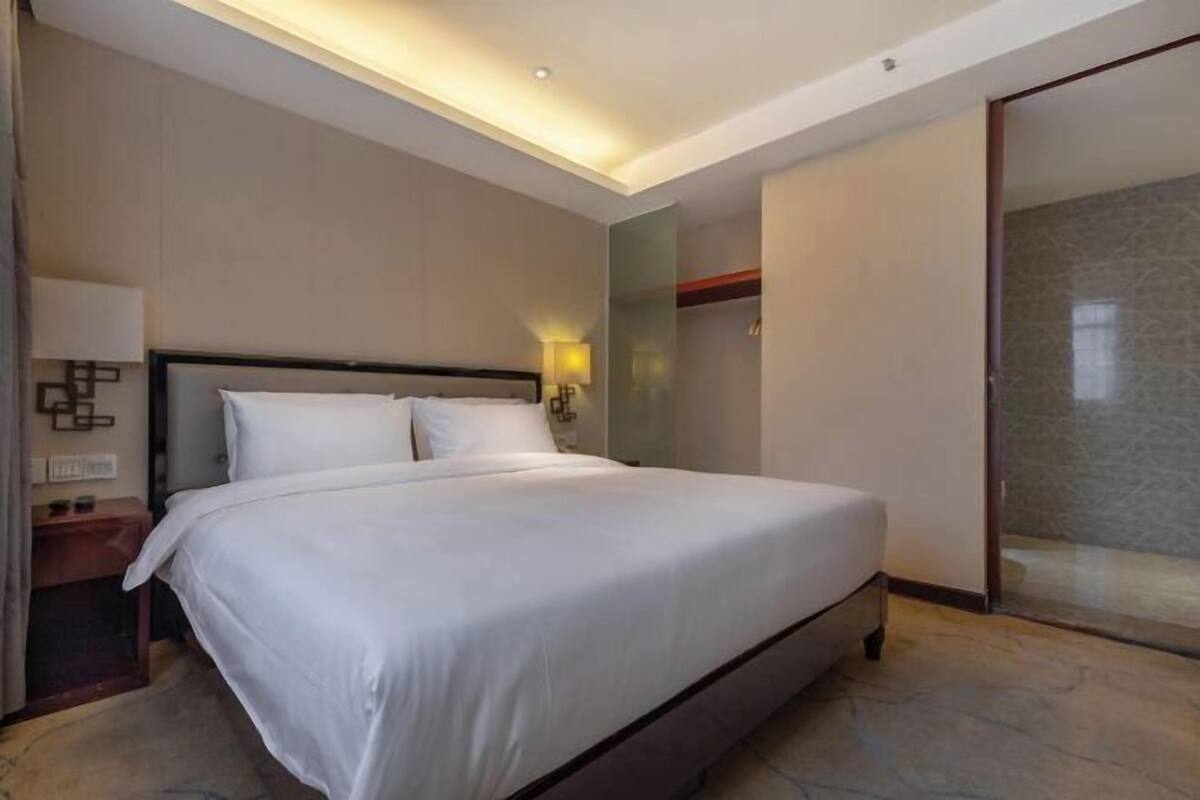 A hotel room with a large bed, bedside lamps, a nightstand, and a sliding door leading to a bathroom.