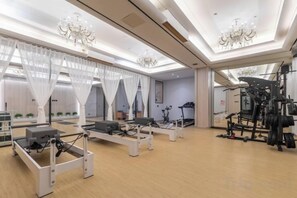 Habitación amplia con una cama grande, un escritorio y una silla. Hay cortinas y un candelabro.