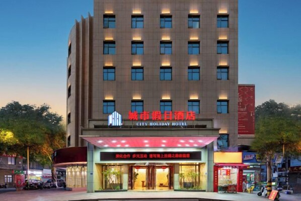 Un hotel de varios pisos con un letrero llamativo del 'City Holiday Hotel'.
