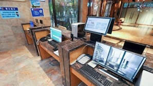 A reception desk with multiple computer stations, a telephone, and a computer monitor displaying a building's interior. - Quanzhou City Holiday Hotel (Gucheng Branch) (Quanzhou)