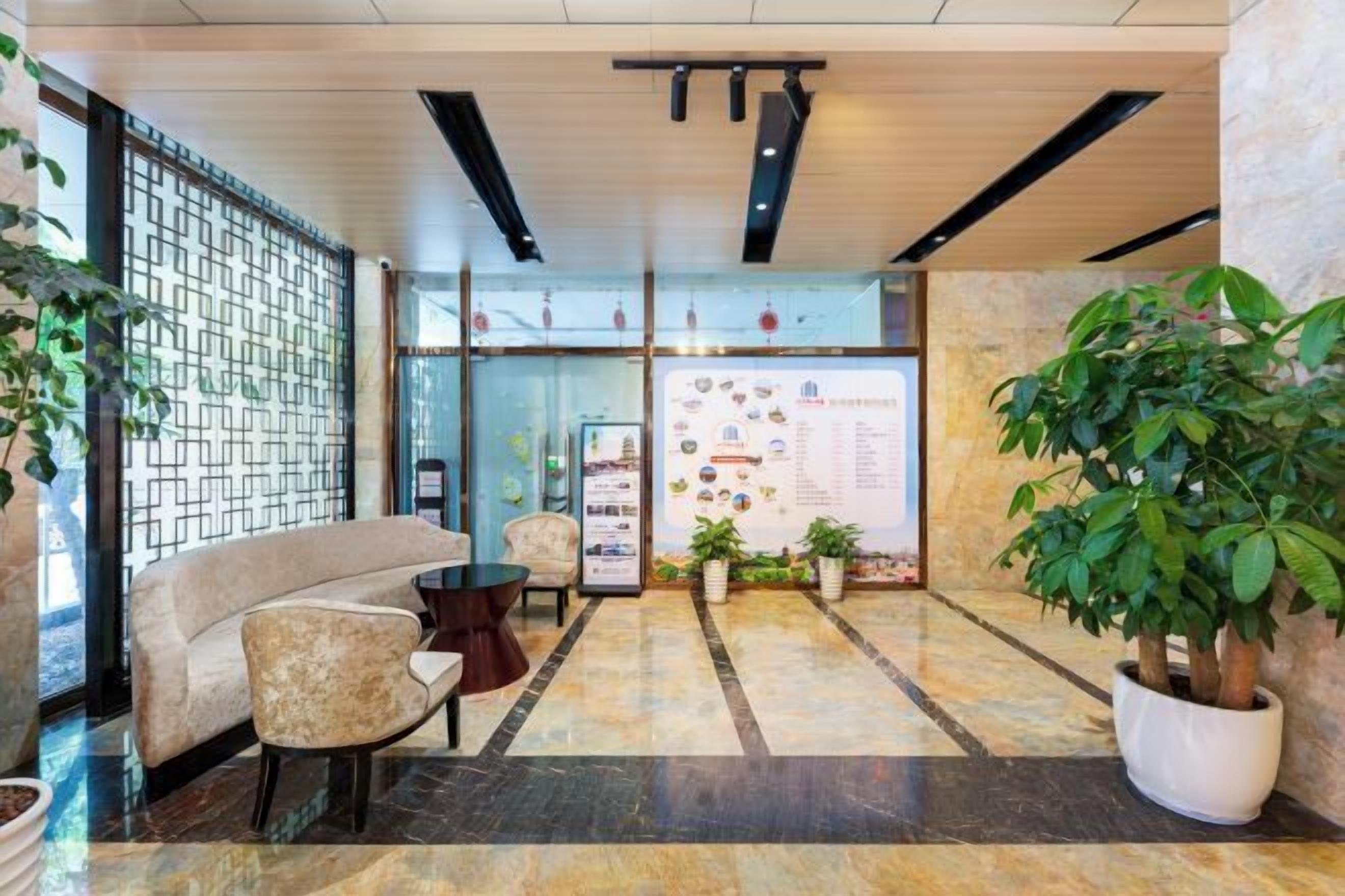 A lobby with a sofa, chairs, a reception desk, and a potted plant.