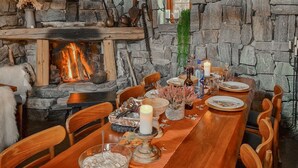 Un comedor con chimenea de piedra, una mesa de madera, sillas y una variedad de vajilla, incluyendo platos, vasos y velas.
