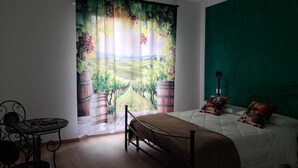 A bedroom with a bed, a table, and a view of a vineyard through a curtain. - B&B 8380 La Cantina di Piero e 'Netta (Manciano)