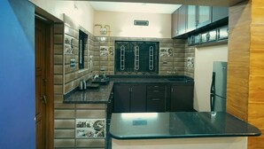 Una cocina compacta con encimera negra, armarios oscuros y horno empotrado.