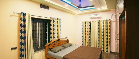 A bedroom with a bed, curtains, a ceiling fan, and an air conditioning unit.