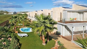 Un hôtel moderne doté d’une piscine, de palmiers et d’un espace extérieur couvert.