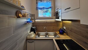 A modern kitchen with a built-in stove, double sink, and wooden cabinetry. - Galactic Sea: delightful cottage surrounded by greenery just minutes from the beach (Lido delle Nazioni)