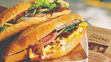 Two sandwiches on a white plate with a newspaper underneath.