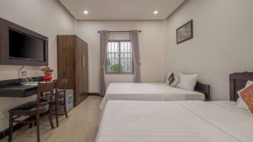 Habitación de hotel con dos camas, un escritorio con silla, televisor montado en la pared y una ventana con cortinas.