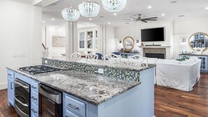 A spacious kitchen with a large island, modern appliances, and decorative lighting. - Step into the blue, stay in the moment at Azure / Golf Cart / 4 Bikes (Santa Rosa Beach)