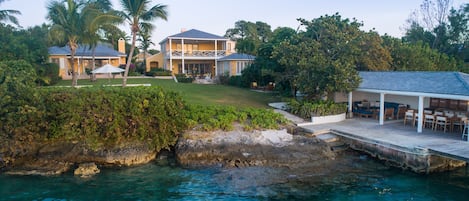 A coastal property with a large house, a covered patio, and a view of the ocean.