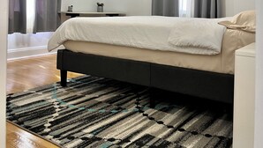 Ein Schlafzimmer mit Bett, Deckenventilator, Klimaanlage, Nachttisch und einem Fenster mit Vorhängen.
