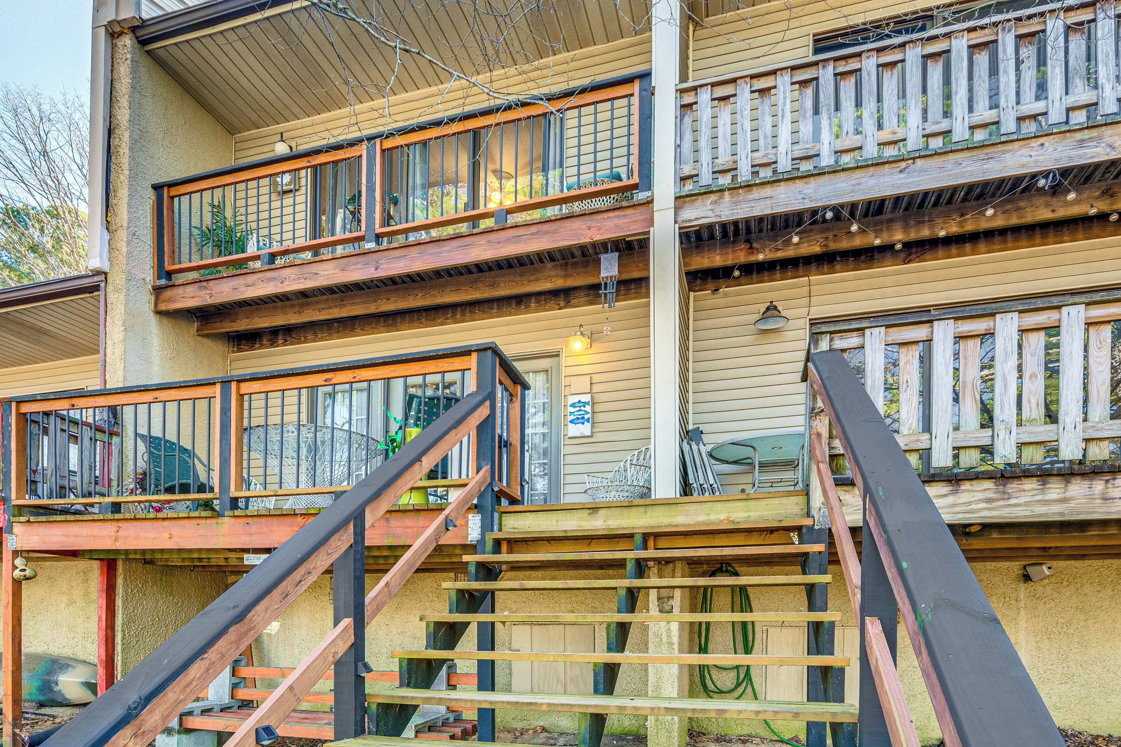 Un immeuble à plusieurs étages doté de balcons en bois, d’un escalier et de mobilier d’extérieur.