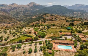 A rural landscape with a large swimming pool, terraced fields, and scattered buildings. - Beautiful apartment in Collesano (PA) (Collesano (PA))