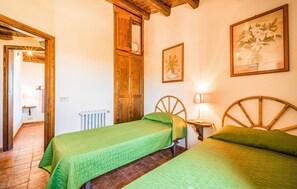 A room with two beds, a wooden door, a radiator, and a framed picture on the wall. - Beautiful apartment in Collesano (PA) (Collesano (PA))