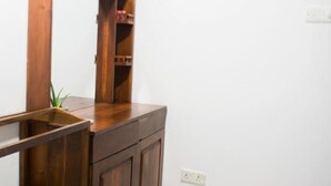 Une commode en bois avec un miroir, une étagère et une plante.