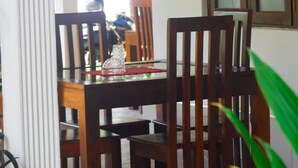 Un coin repas avec des chaises en bois et une table, un vase en verre et un set de table rouge.