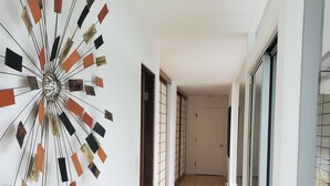 Un couloir doté d’un plafond au design moderne, d’un plancher en bois et de grandes portes coulissantes en verre d’un côté.