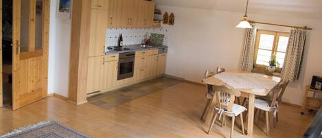 A kitchen with wooden cabinets, a dining table, and chairs.