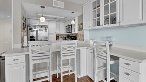 Een moderne keuken met witte kasten, een centraal eiland met barstoelen en hanglampen.