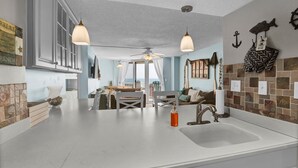 Een moderne keuken met een groot eiland, hanglampen en een nautisch thema.