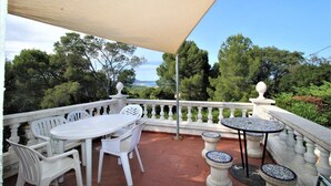 A balcony with a table and chairs, a pergola, and a view of trees and the sea. - Apartment in Playa de Pals Near Sandy Beach (Pals)