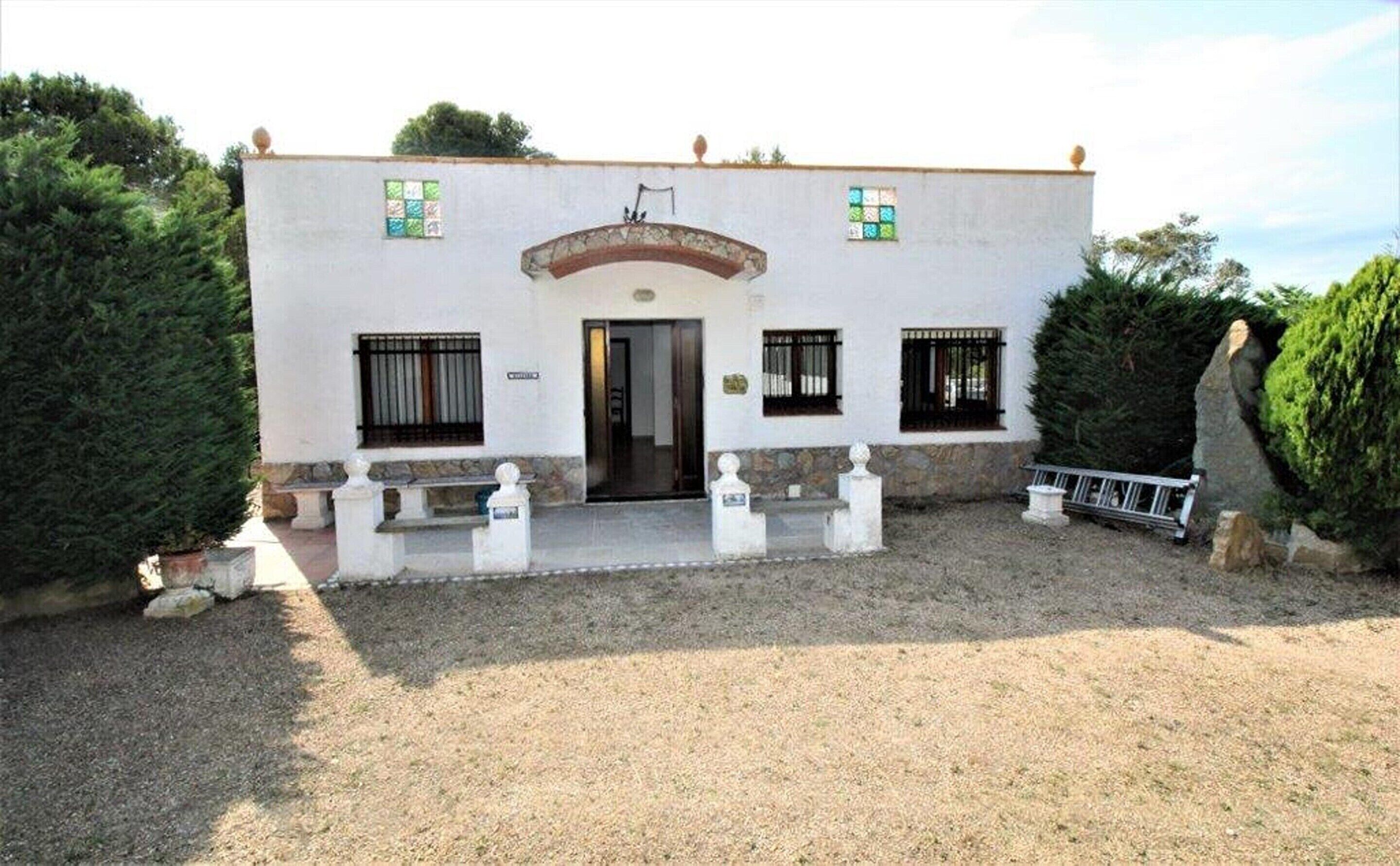 A two-story building with a central entrance, a small porch, and a gravel driveway.