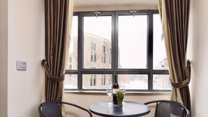 Une pièce avec une table ronde, deux chaises, une bouteille de vin et un vase.