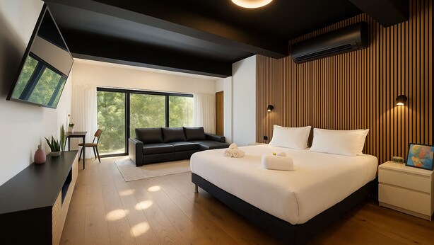 Une chambre d’hôtel moderne avec un grand lit, un canapé noir, un bureau et une télévision.