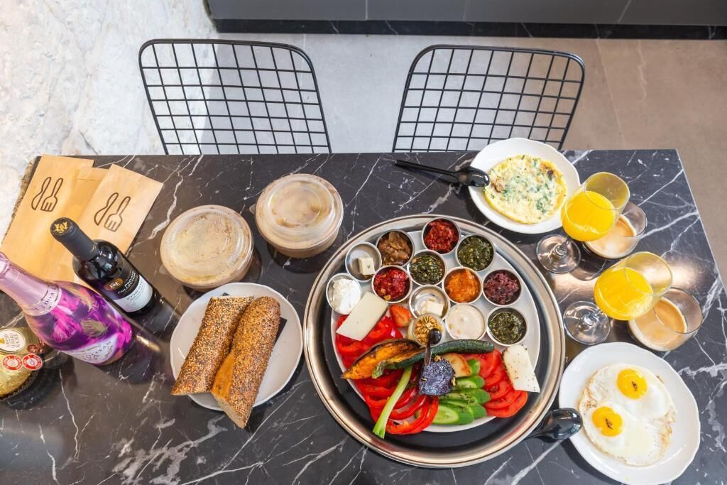 A breakfast setting with a variety of dishes, drinks, and a bottle of wine on a marble table.