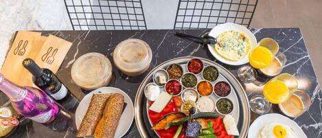 Un desayuno con una variedad de platillos, bebidas y una botella de vino sobre una mesa de mármol.