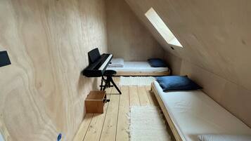 Ein gemütliches Dachzimmer mit Klavier, zwei Betten und einem Oberlicht.