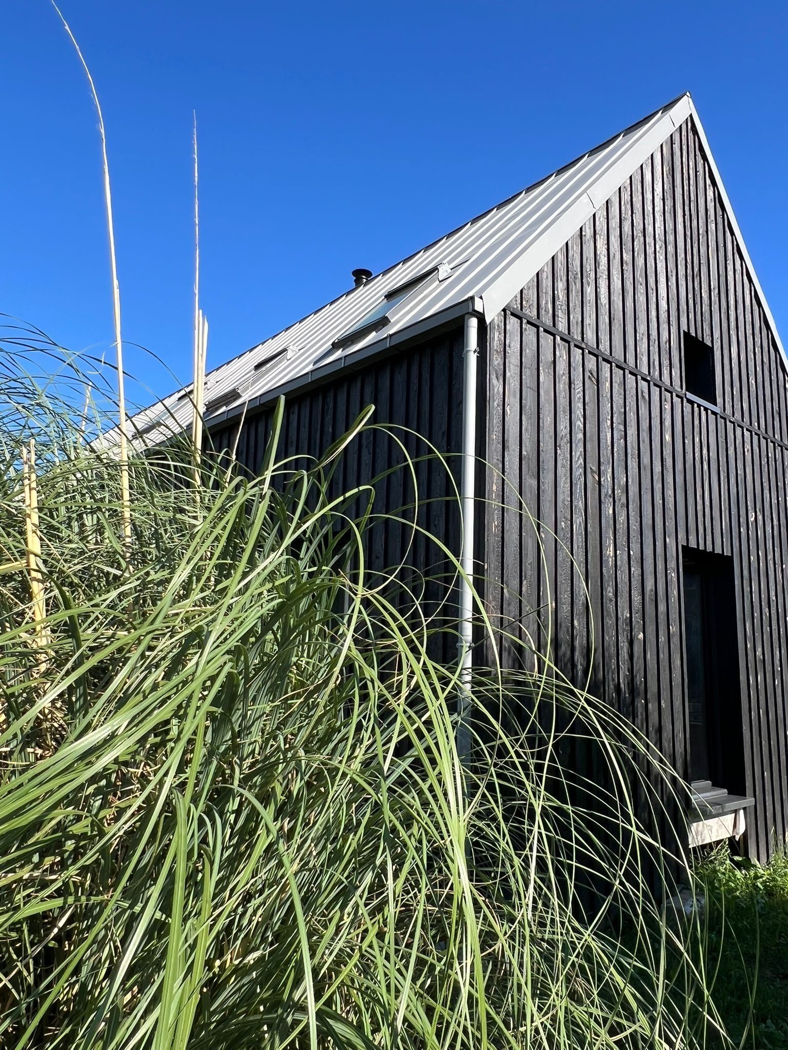 Ein rustikales Holzhaus mit geneigtem Dach und einem kleinen Fenster.