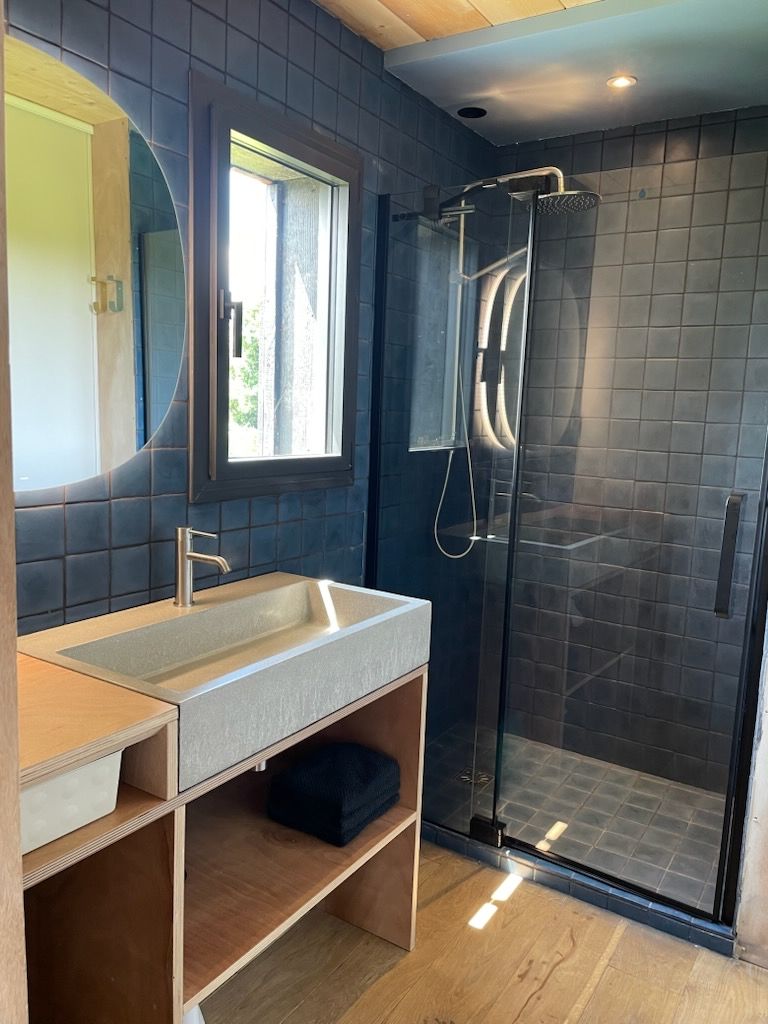 Un bagno moderno con uno specchio grande, un lavandino e una cabina doccia in vetro.
