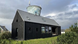 Ein rustikales, auf Scheune gestaltetes Gebäude mit Metalldach, großen Fenstern und einem Wasserturm im Hintergrund.