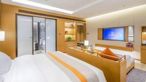 Une chambre d’hôtel équipée d’un lit, d’un bureau, d’une télévision et d’une porte coulissante.