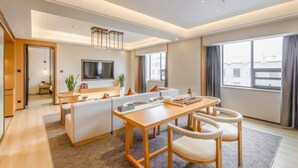 Une chambre d’hôtel moderne dotée d’un coin repas, d’un téléviseur à écran plat et de grandes fenêtres.